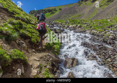 Les touristes de montagne aller en haut de la colline le long de la rivière turbulente dans les montagnes du Caucase Banque D'Images