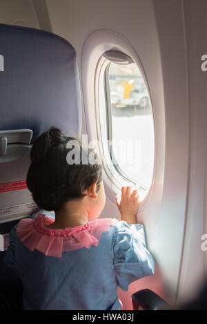 Petite fille voyageant par avion. Enfant assis par avion et à l'extérieur de la fenêtre. Banque D'Images