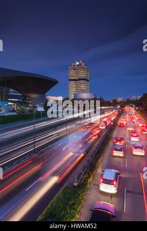 Germany, Bavaria, Munich, BMW Welt showroom de l'entreprise, siège de l'entreprise BMW et BMW Museum avec trafic du soir Banque D'Images