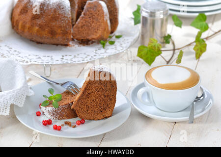 Du gâteau en forme de bague avec du chocolat, des 'Gugelhupf" en Autriche et Allemagne, servi avec une tasse de cappuccino Banque D'Images