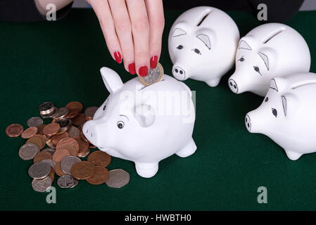 Woman's hand with red nails en plaçant l'argent dans une tirelire Banque D'Images