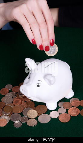 Woman's hand with red nails en plaçant l'argent dans une tirelire Banque D'Images