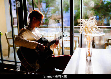 L'homme artiste asiatique jouer guitare acoustique dans la fenêtre près de cafe Banque D'Images