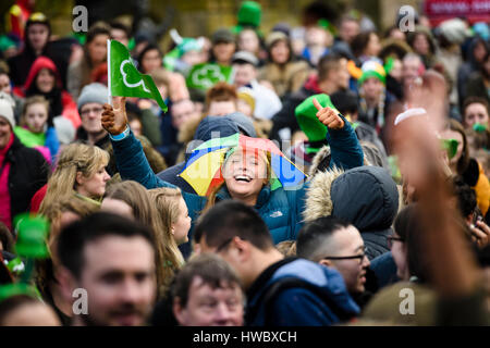 Belfast, Irlande du Nord. 17 Mar 2016 - une jeune femme dans la foule, portant un chapeau parapluie donne le coup de signer alors qu'elle célèbre la Saint Patrick's Day. Banque D'Images