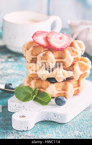 Pile de gaufres belges faites maison avec des fraises, bleuets et sirop de table bleu Banque D'Images