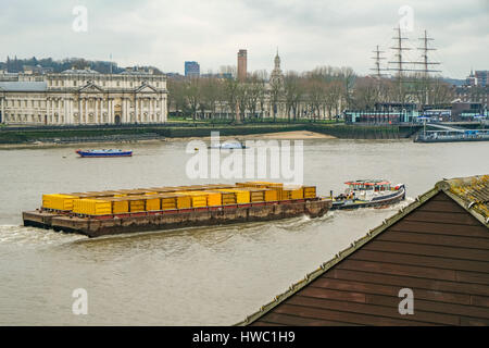 Les conteneurs jaune tirant chaland qui passe par Greenwich avec vue sur le fleuve. Pris dans l'hiver sur un après-midi. L'élimination des déchets à Londres. Banque D'Images