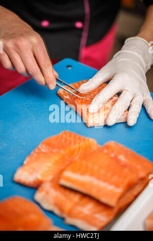 Chef, c'est la dépose de l'os de poissons saumon avec pince à épiler Banque D'Images