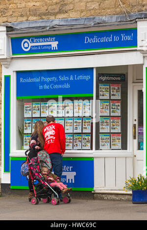 Cirencester - Couple avec enfant en poussette à la fenêtre de propriétés en vente et location, Cirencester, Gloucestershire Cirencester en Mars Banque D'Images