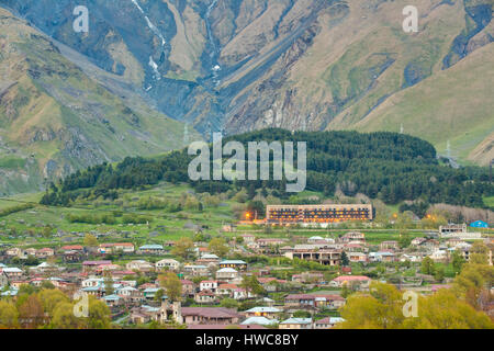 Stepantsminda Village au soir ou la nuit sur fond de montagne dans la région de Kazbegi district, région de Mtskheta-Mtianeti, Géorgie. Printemps ou été, Banque D'Images