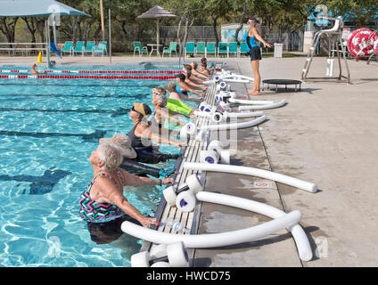 Groupe de femmes (de divers âges) participant à un cours d'aérobic aquatique, instructeur démontrant « l'exercice d'étirement approprié », haltères en styromousse et nouilles d'eau. Banque D'Images