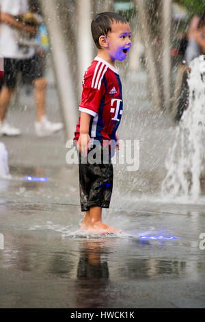 Portrait vertical d'un petit garçon jouant dans la place de la fontaine à Singapour. Banque D'Images