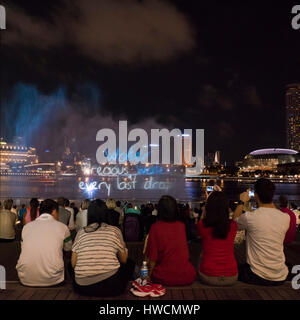 Vue sur place de spectateurs photographier l'étonnant spectacle son et lumière complet de nuit à Singapour. Banque D'Images
