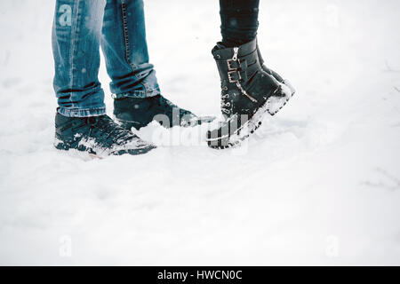 Embrassant les jambes des couples debout sur la neige Banque D'Images