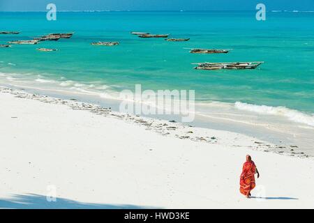 La Tanzanie, Zanzibar, Jambiani, voilée femme marche sur une plage de sable blanc baignée par les eaux turquoise Banque D'Images
