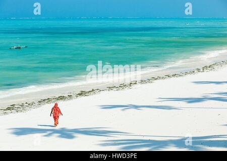 La Tanzanie, Zanzibar, Jambiani, voilée femme marche sur une plage de sable blanc baignée par les eaux turquoise Banque D'Images