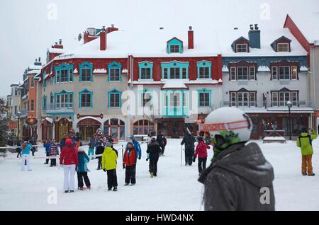 Le Canada, la province du Québec, région des Laurentides, Mont Tremblant, le ski et les enfants dans l'ensemble de ski en face de bâtiments colorés de la station de sports d'hiver Banque D'Images