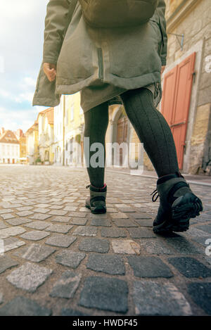 Low angle view of woman with backpack marche sur la rue pavée de la vieille ville européenne en pavées Banque D'Images