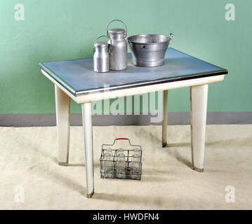 Still Life de Table Rétro avec haut bleu et blanc avec les jambes et les cruches de métal sur le dessus du godet et l'étui de la bouteille de lait en verre en dessous Banque D'Images
