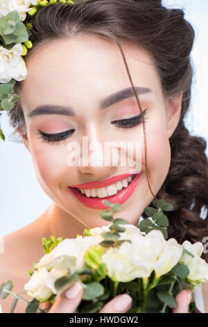 Portrait of smiling woman holding bouquet de fleurs sur fond blanc Banque D'Images