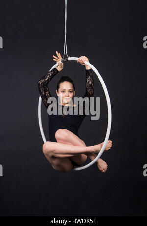 Acrobat aérien dans l'anneau. Une jeune femme exécute les éléments acrobatiques dans l'anneau d'air. Des performances en studio sur fond noir. Banque D'Images