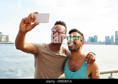 Deux jeunes hommes en tenant sur le bord de selfies smartphone, New York, USA Banque D'Images