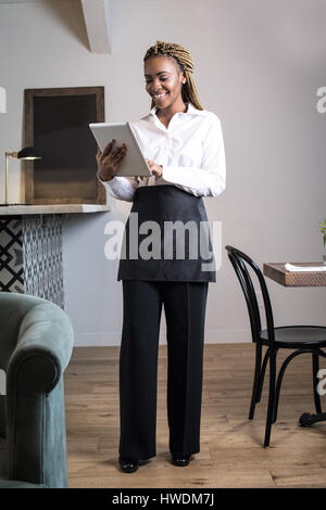 Portrait de serveur dans un restaurant, using digital tablet Banque D'Images