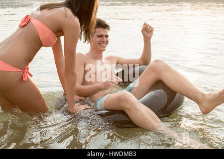Les amis s'amusant avec anneau gonflable dans river Banque D'Images