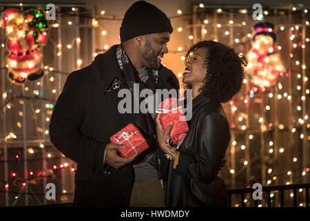 Romantic couple exchanging christmas gifts at night, New York, USA Banque D'Images