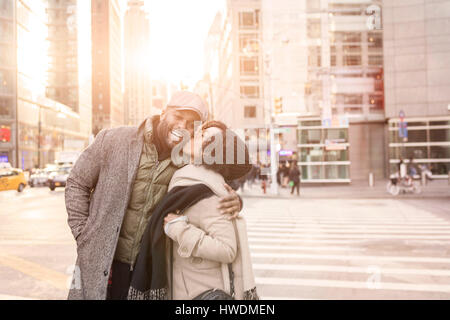 Young woman kissing boyfriend on street, New York, USA Banque D'Images