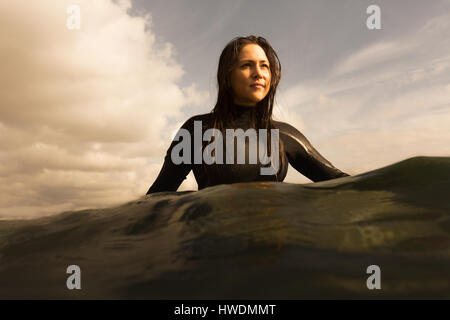 Jeune femme en mer, assis sur une planche de surf, bassin pour enfants Banque D'Images