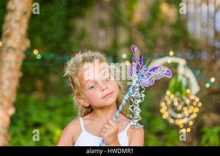 Portrait of young girl holding butterfly wand Banque D'Images