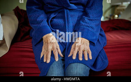 Hauts femme assise sur le bord du lit, mid section Banque D'Images