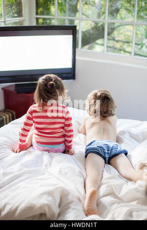 Frère et soeur regarder la télévision on bed Banque D'Images