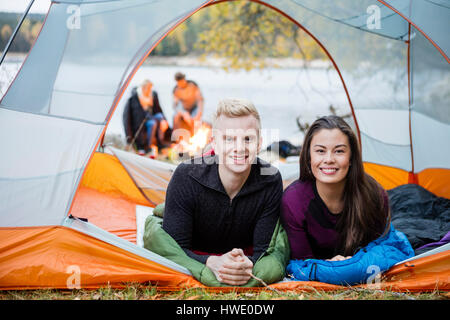 Jeune couple couché dans la tente de camping au bord du lac au cours de Banque D'Images