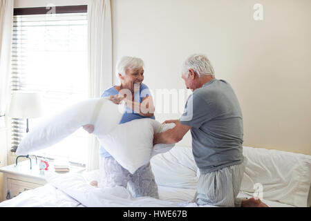 Senior couple having pillow fight sur le lit dans la chambre Banque D'Images