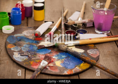 Palette avec de multiples couleurs, l'aquarelle et pinceaux sur table en bois Banque D'Images