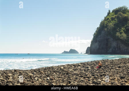 On aime la plage rocheuse après une randonnée dans la Vallée de Pololu à l'extrémité nord de la Grande Île d'Hawaï. Méconnaissable femme assise sur un rocher Banque D'Images