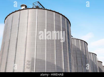 Silos agricoles. Extérieur du bâtiment. L'entreposage et le séchage de céréales, blé, maïs, soja, tournesol contre le ciel bleu avec des nuages blancs Banque D'Images