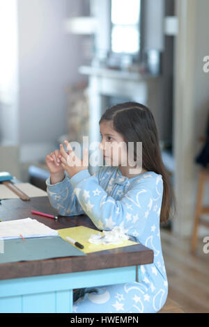 Girl doing homework et compte sur les doigts à table de cuisine Banque D'Images