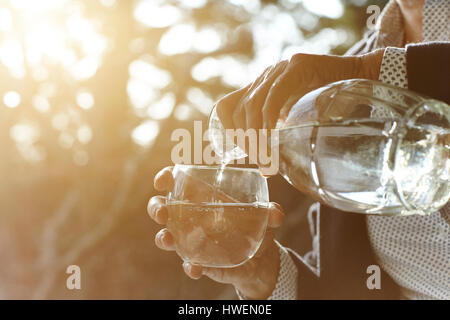 Mains des cadres woman pouring verre d'eau par fenêtre Banque D'Images