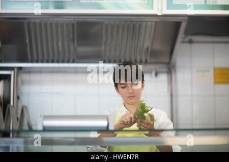 Young woman preparing food in fast food shop Banque D'Images