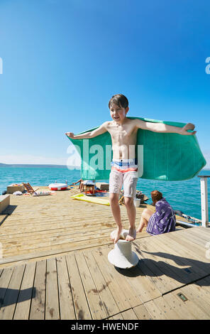 Boy balancing sur bollard sur péniche pont soleil, Kraalbaai, Afrique du Sud Banque D'Images