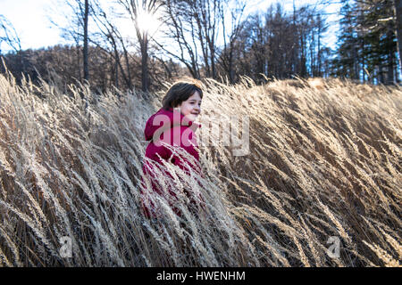 Jeune garçon jouant dans l'herbe haute Banque D'Images