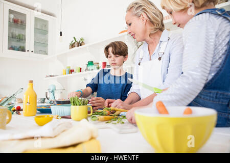 Femme mature la préparation des légumes à table de la cuisine avec son fils et sa fille Banque D'Images