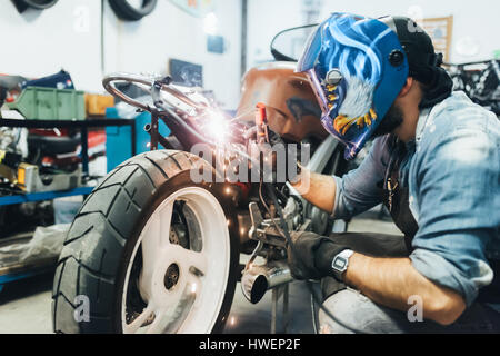 Homme mûr, travaillant sur la moto dans le garage Banque D'Images