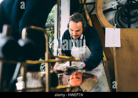 Métallier marteler le cuivre dans l'atelier de forge Banque D'Images