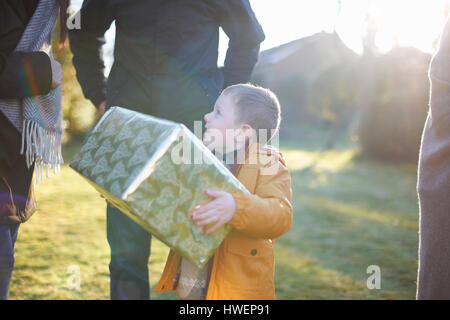 Happy boy carrying présent avec la famille dans le jardin Banque D'Images