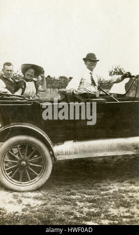 Meubles anciens c1915 photo, deux hommes et une femme dans un c1915 touring Ford, avec de la publicité pour des pneus Swinehart sur le côté. Lieu : New York, USA. Voir Alamy HWF0BK pour une autre vue de cette image. SOURCE : tirage photographique original. Banque D'Images