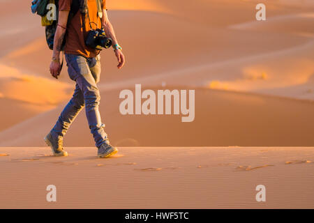 Un homme marche sur les dunes du désert du Sahara au coucher du soleil Banque D'Images