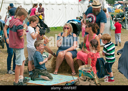 Une famille assis sur des balles de foin en face de nourriture tentes un pique-nique au Port Eliot Cornwall Festival Banque D'Images